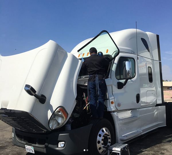man replacing semi truck windshield on side of the road
